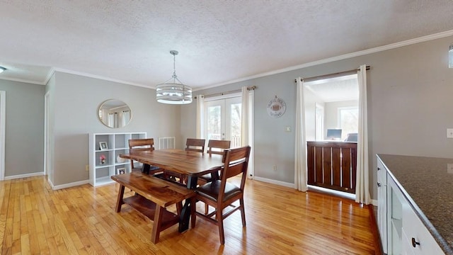 dining area with a textured ceiling, light hardwood / wood-style floors, an inviting chandelier, and crown molding