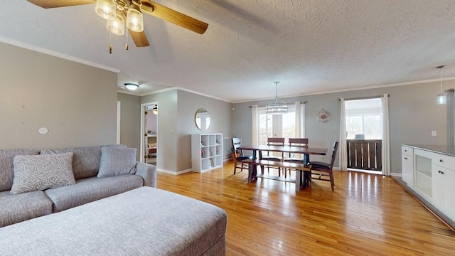 living room with a textured ceiling, light hardwood / wood-style floors, ceiling fan, and ornamental molding