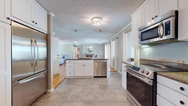 kitchen featuring kitchen peninsula, crown molding, decorative light fixtures, white cabinets, and appliances with stainless steel finishes