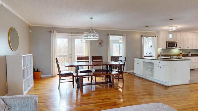 dining space featuring french doors, sink, crown molding, a textured ceiling, and light wood-type flooring