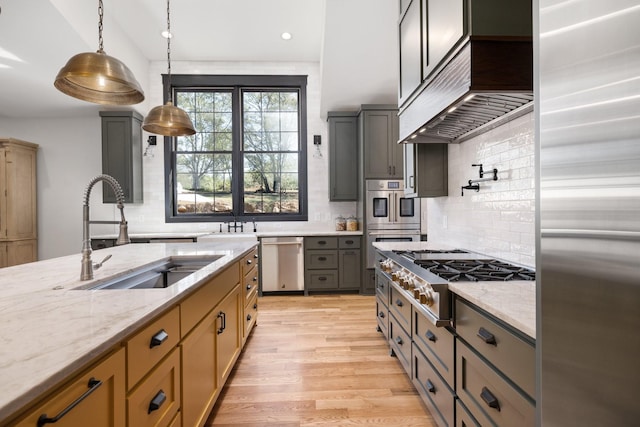 kitchen featuring custom exhaust hood, sink, light stone countertops, decorative light fixtures, and stainless steel appliances