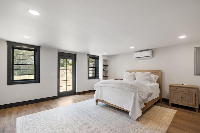 bedroom with a wall mounted air conditioner and hardwood / wood-style flooring