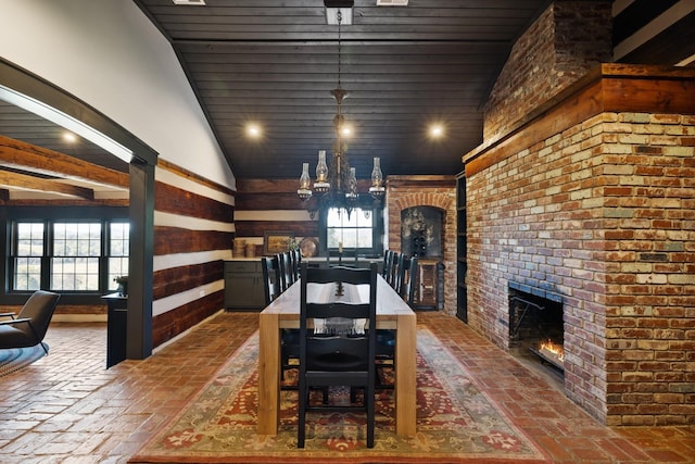 dining space with a notable chandelier, lofted ceiling, and a brick fireplace