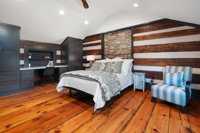 bedroom featuring ceiling fan, light hardwood / wood-style floors, built in desk, and vaulted ceiling