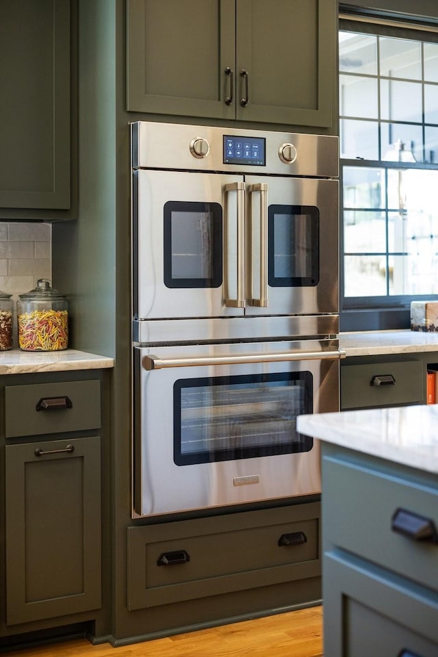 kitchen with tasteful backsplash, double oven, and green cabinets