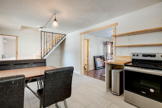 kitchen with a wall mounted AC, stainless steel range with electric cooktop, wooden counters, and a textured ceiling