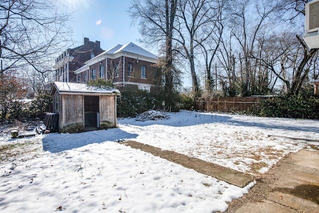 snowy yard with a storage shed