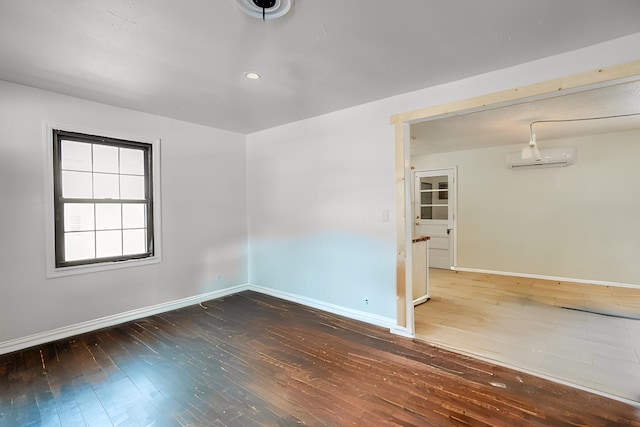 spare room with an AC wall unit and dark hardwood / wood-style floors