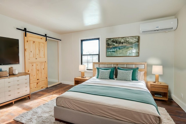 bedroom featuring a barn door, wood-type flooring, and a wall mounted air conditioner