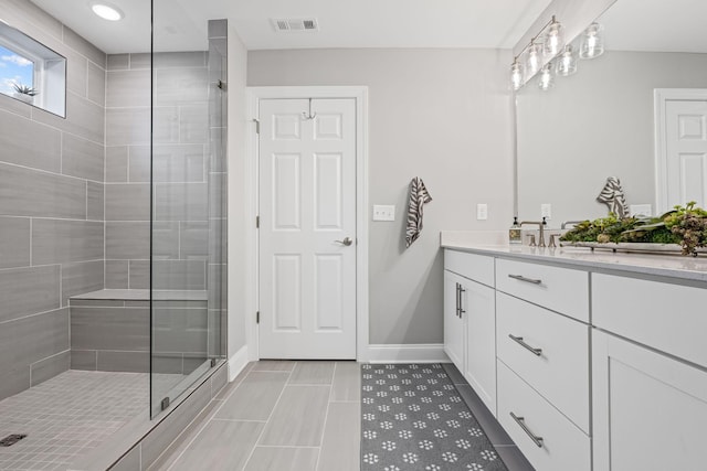 bathroom featuring a tile shower, tile patterned flooring, and vanity