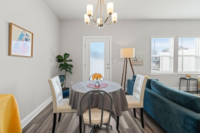 dining space featuring dark wood-type flooring and an inviting chandelier