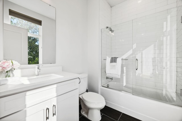 full bathroom with combined bath / shower with glass door, tile patterned floors, vanity, and toilet