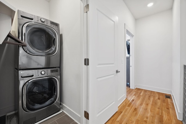 laundry area featuring hardwood / wood-style flooring and stacked washer / dryer