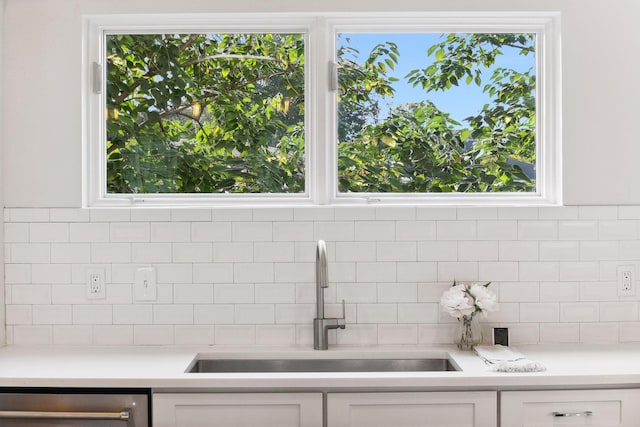 interior space featuring dishwasher, tasteful backsplash, white cabinetry, and sink