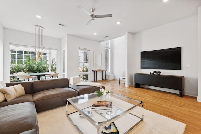 living room with light hardwood / wood-style flooring and ceiling fan with notable chandelier