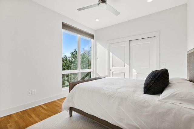 bedroom featuring hardwood / wood-style flooring, ceiling fan, a closet, and multiple windows