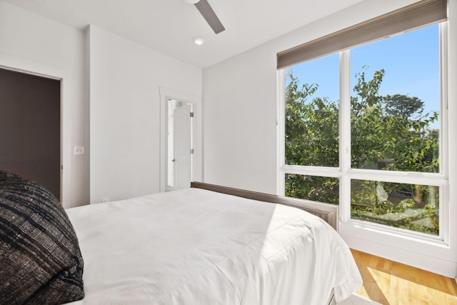 bedroom featuring ceiling fan, wood-type flooring, and multiple windows