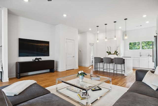 living room with light hardwood / wood-style floors and sink