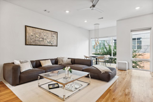 living room with hardwood / wood-style floors and ceiling fan with notable chandelier