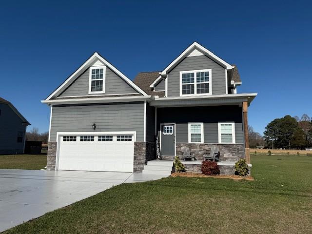 craftsman inspired home with a porch, a front yard, stone siding, and driveway