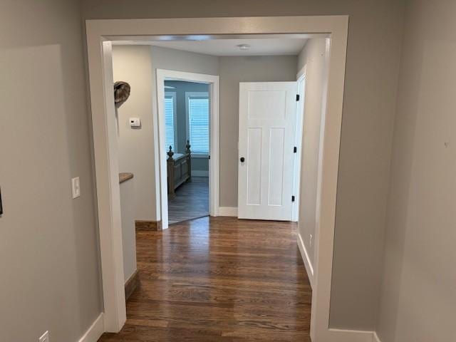 corridor with dark wood finished floors and baseboards