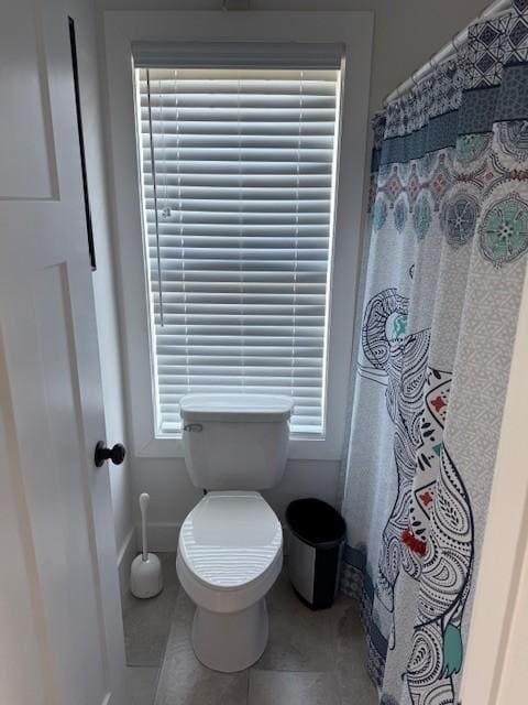 bathroom featuring toilet, baseboards, a shower with shower curtain, and tile patterned floors