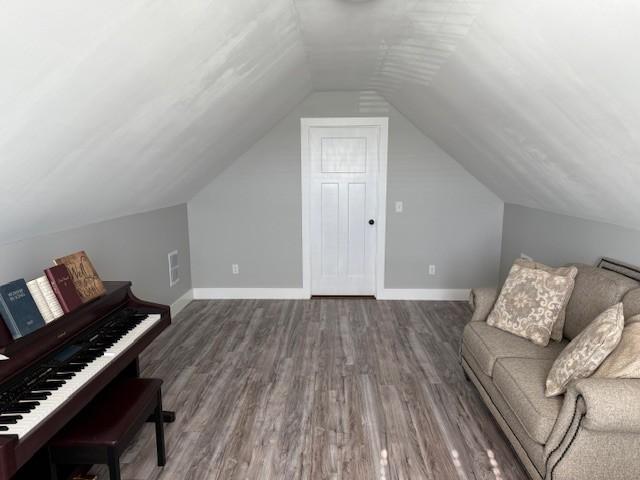 sitting room with lofted ceiling, visible vents, baseboards, and wood finished floors