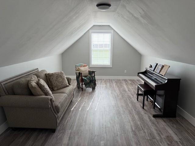 living area with lofted ceiling, wood finished floors, and baseboards