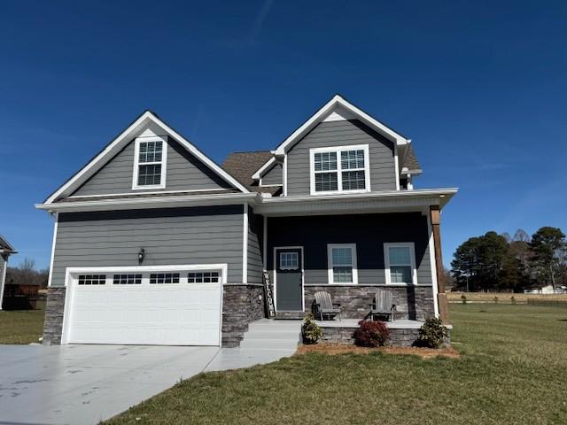 craftsman-style house with covered porch, stone siding, a front lawn, and concrete driveway