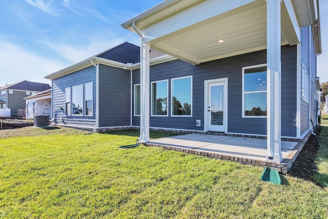 rear view of house with a lawn, central AC, and a patio