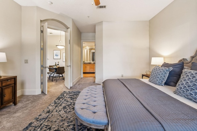 bedroom with light carpet, connected bathroom, and ceiling fan