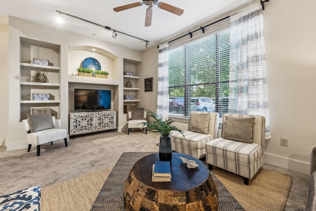 carpeted living room featuring built in shelves and ceiling fan