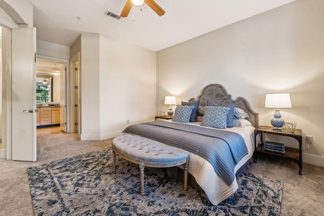 carpeted bedroom with ensuite bath and ceiling fan