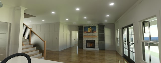 living room featuring built in features, french doors, a stone fireplace, and crown molding