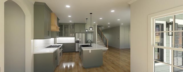 kitchen featuring wood-type flooring, decorative light fixtures, decorative backsplash, a center island with sink, and appliances with stainless steel finishes