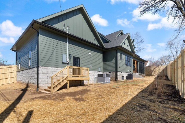 back of house with central AC unit, a shingled roof, and a fenced backyard