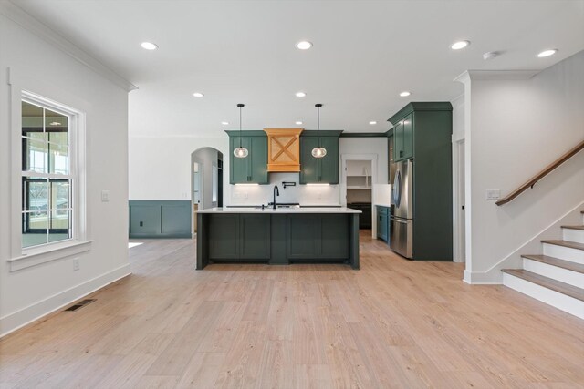 kitchen with visible vents, green cabinetry, arched walkways, freestanding refrigerator, and light countertops