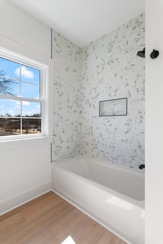 bathroom with baseboards, a bathtub, and wood finished floors