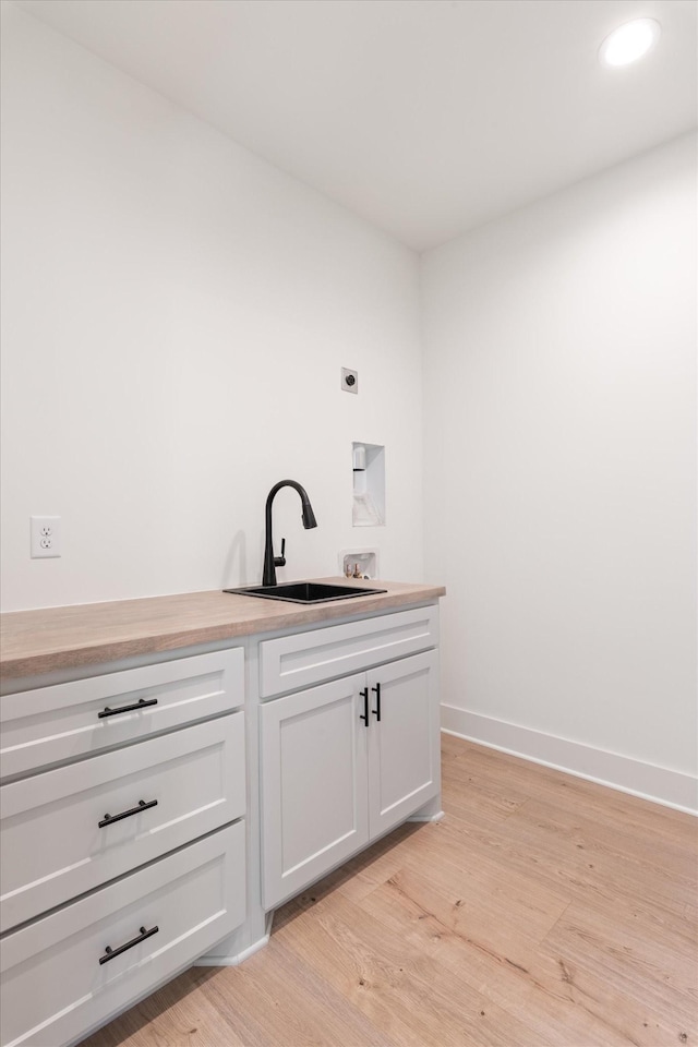 bar featuring a sink, baseboards, light wood-style floors, and recessed lighting