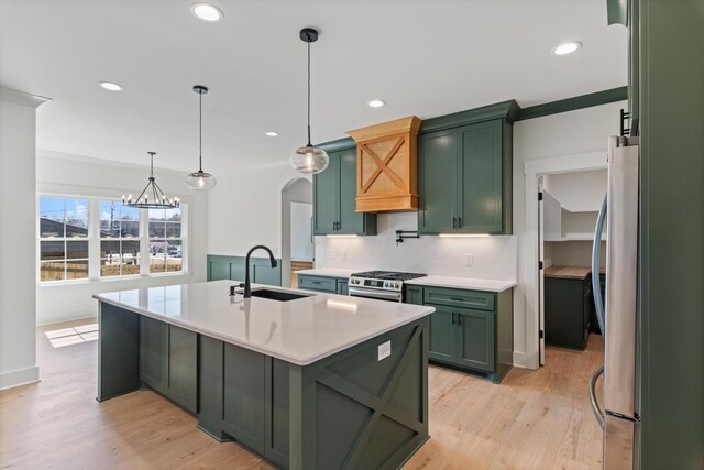 kitchen featuring a sink, light wood-style floors, green cabinetry, and appliances with stainless steel finishes