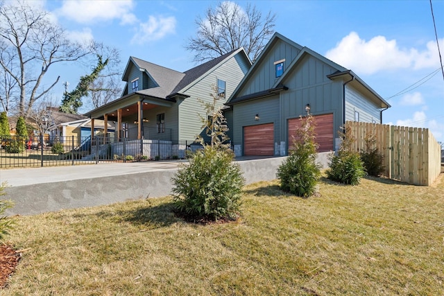 view of front of home featuring driveway, a garage, board and batten siding, and a fenced front yard