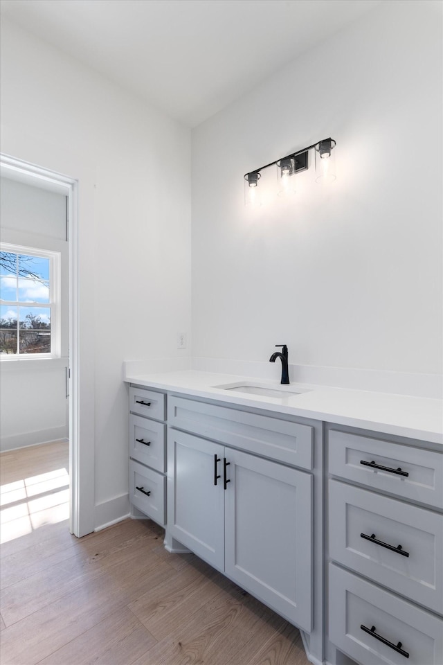 bathroom with vanity, wood finished floors, and baseboards