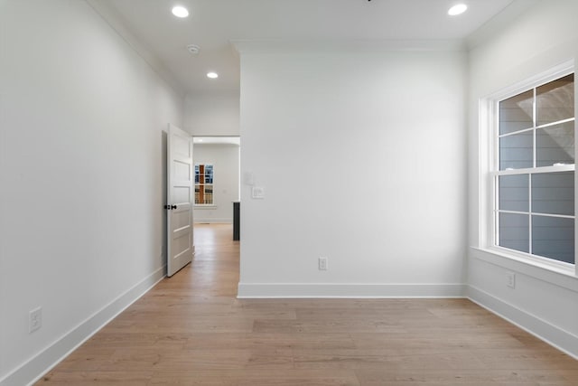 empty room with recessed lighting, crown molding, light wood-type flooring, and baseboards