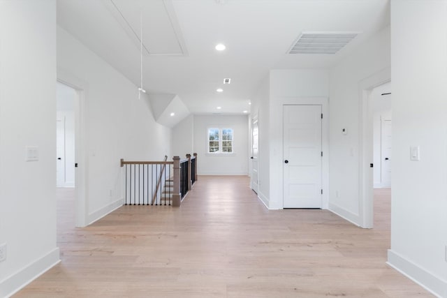 hall featuring an upstairs landing, visible vents, light wood-style flooring, and attic access