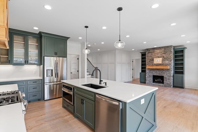 kitchen featuring light wood-style flooring, appliances with stainless steel finishes, light countertops, and a sink