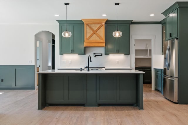 kitchen with green cabinets, stainless steel fridge with ice dispenser, light countertops, light wood-style flooring, and arched walkways