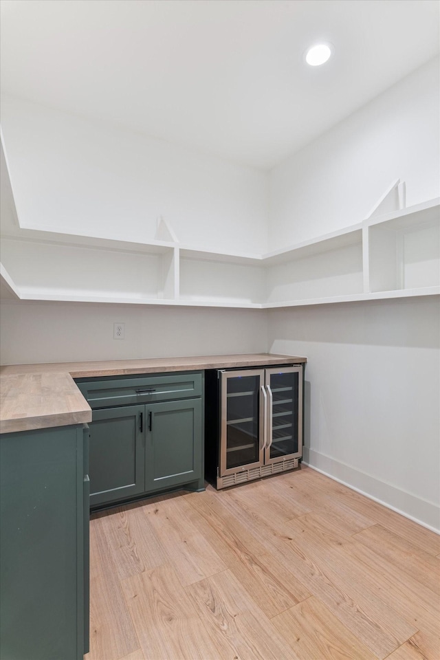 bar featuring baseboards, wine cooler, recessed lighting, light wood-style floors, and a bar