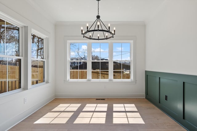 unfurnished dining area with visible vents, a healthy amount of sunlight, crown molding, and light wood finished floors