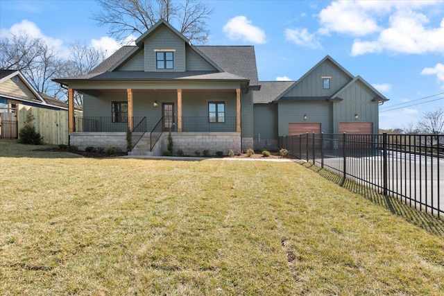 view of front facade featuring fence, a porch, concrete driveway, a front lawn, and board and batten siding