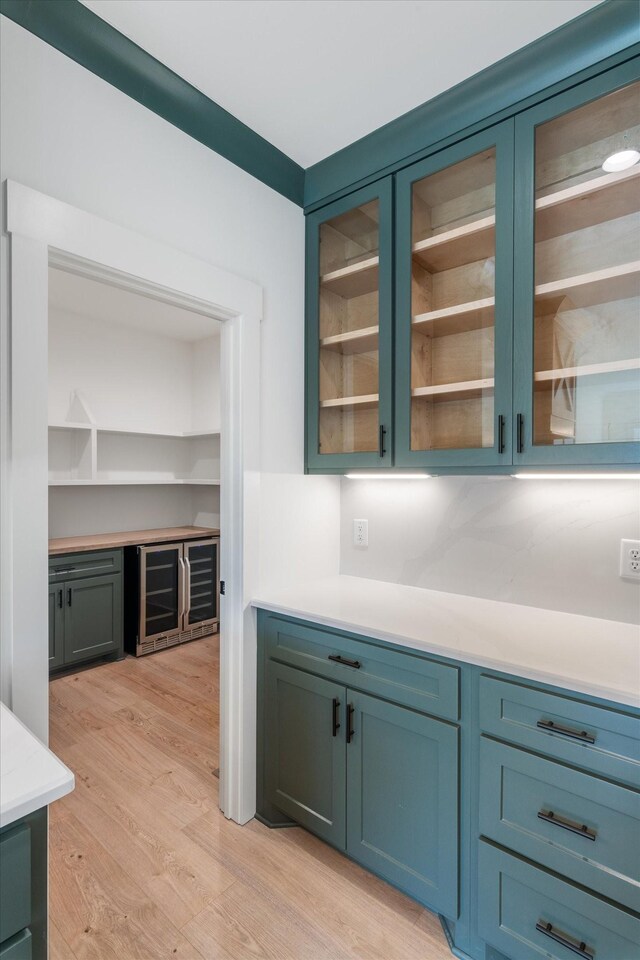 kitchen with glass insert cabinets, light wood-style flooring, light countertops, and wine cooler